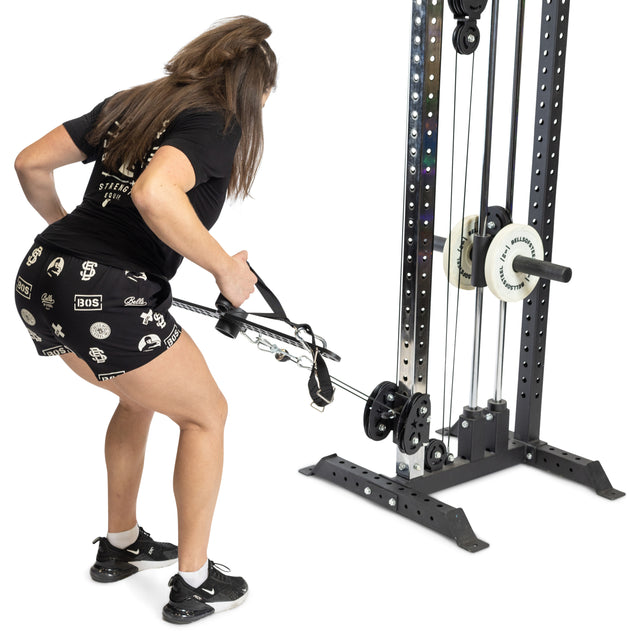A person in black athletic wear performs a bent-over row on a cable machine using the Bells of Steel 30 D-Handle Bar Cable Attachment with Carabiners, pulling it toward their torso against a white background.