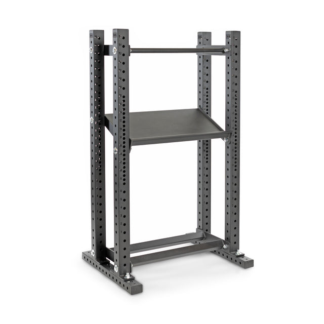 The Hydra Flat Foot Components by Bells of Steel is a gray metal rack that acts as a power rack, offering multiple adjustable settings. It features a rectangular base with flat foot support, two vertical supports, and a top bar with a central shelf. Ideal for weightlifting and gym use.