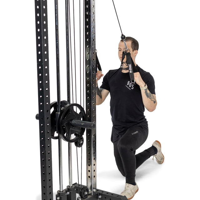 A person kneels on one knee while performing a cable face pull at the gym, gripping Bells of Steel Aluminum Handles Pair with both hands.