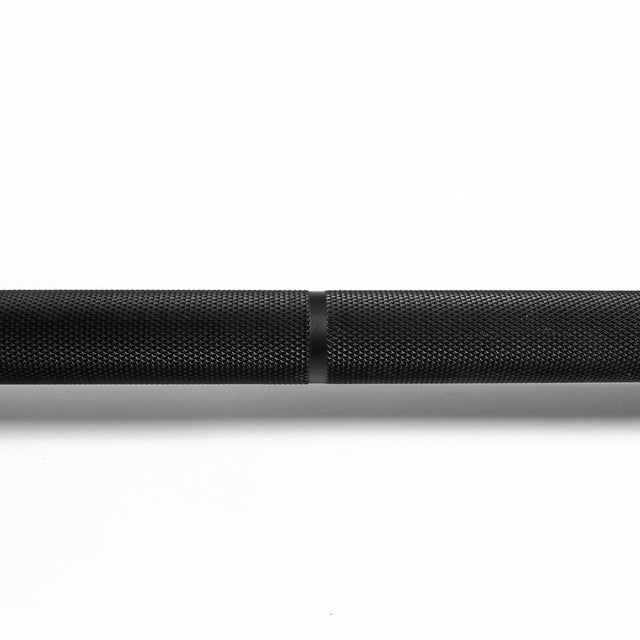 A close-up of the Bells of Steel Powerlifting Bar’s textured black metal finish and center knurling detail, meeting IPF specs, shown against a white background at the intersection of two bar sections.