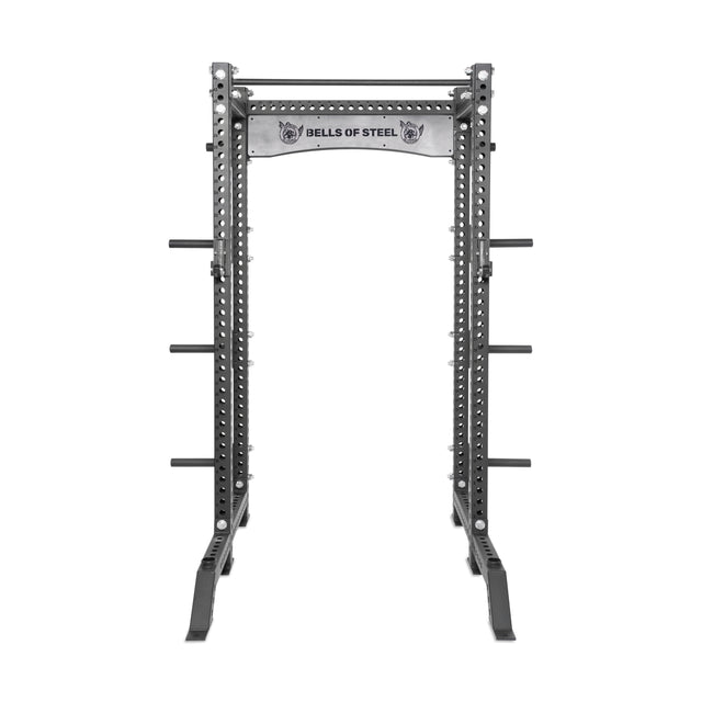 The Bells of Steel Manticore Collegiate Power Rack Builder features 3"x3" uprights, 1" holes for attachments, side storage pegs for weight plates, and a top pull-up bar—ideal for any home gym. "Bells of Steel" is displayed on the front panel.