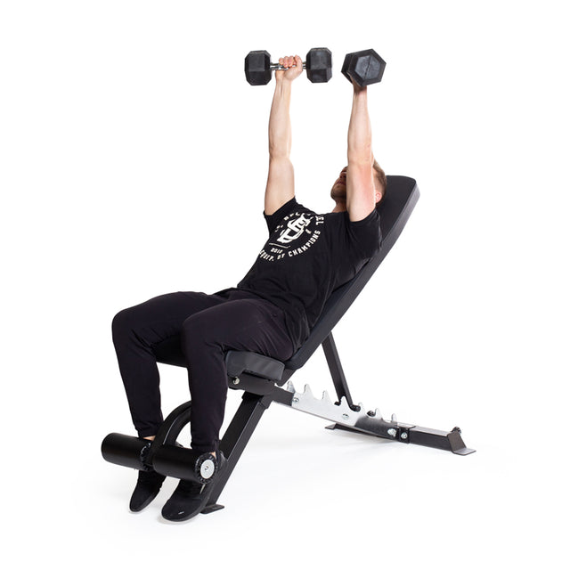 A person in black workout clothes performs an incline dumbbell press on an incline bench, holding Bells of Steel Ergo Rubber Hex Dumbbell Sets, arms extended upward against a white background.