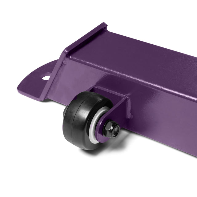 Close-up of a heavy-duty purple metal component from the Buzz-Saw Heavy-Duty Adjustable Bench by Bells of Steel, featuring a black and silver caster wheel on a rectangular frame with an attachment hole.