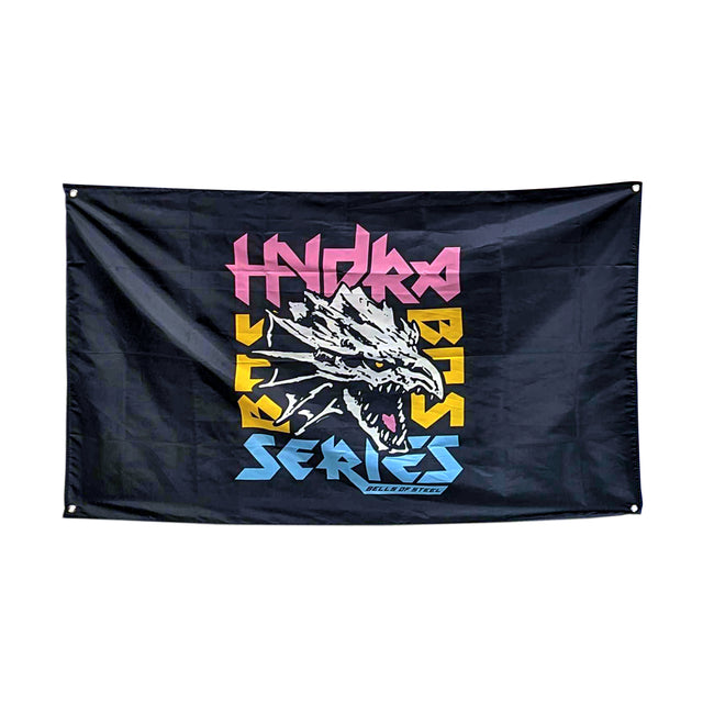 The Bells of Steel Flags feature a black background with a striking white dragon head at the center, mouth open. "Hydra Series" in pink, yellow, and blue sits above and below; "Rise of the Elite" appears beneath. Ideal for gym decor.