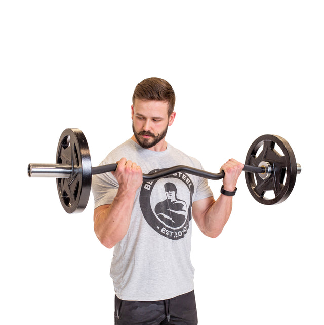 A man in a gray t-shirt performs a bicep curl with the Bells of Steel EZ Curl Bar (45"), concentrating on arm development as he looks down at the weight, set against a white background.