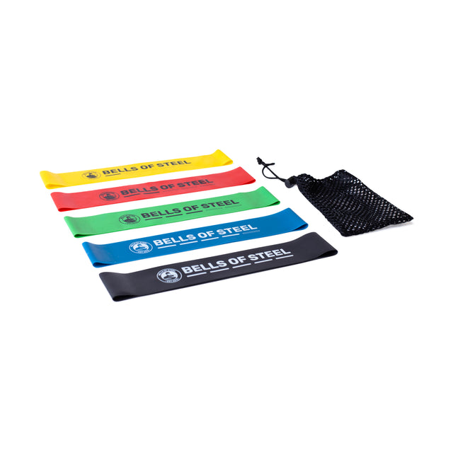 The Bells of Steel Mini Bands, in yellow, red, green, blue, and black with a black mesh pouch, are essential gym accessories displayed on a white background.