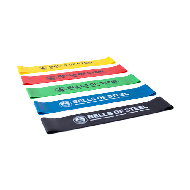Five Bells of Steel Mini Bands, in yellow, red, green, blue, and black—each labeled with the brand—are arranged diagonally on a white background. Perfect as gym accessories or for resistance training.