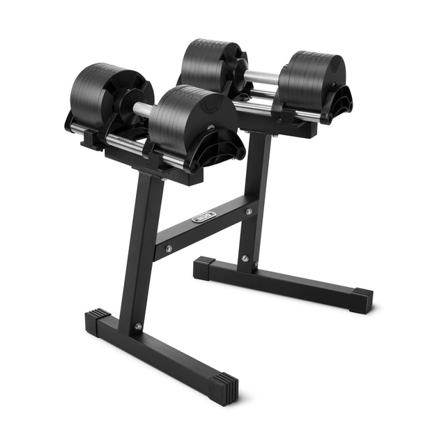 A pair of Nuobell Adjustable Dumbbells with black plates sit on the NÜOBELL Floor Stand by Nuobell, featuring a compact T-shaped base for space-saving storage against a white background.
