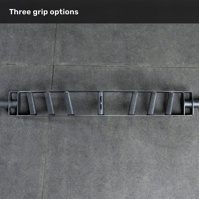 An overhead view of the Bells of Steel Arch Nemesis Swiss Bar—a specialty barbell with three angled grips—rests on a gray tiled floor, labeled "Three grip options" to showcase its versatility as a cable attachment.