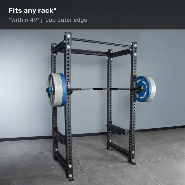 A Bells of Steel Short Rackable Barbell is loaded on j-cups in a black power rack inside a gray room. Text above reads, "Fits any rack* *Within 49” j-cup outer edge—ideal for any home gym.
