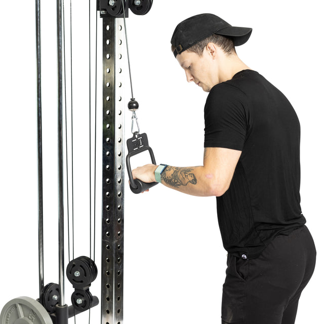 Wearing black athletic gear and a backward cap, a person with a forearm tattoo uses the Bells of Steel Fat Bar - Single D Handle on a cable machine, focusing on grip strength with a one-handed hold.