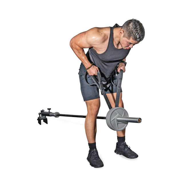 A man in a black tank top and shorts uses the Bells of Steel RocIT Tricep Strap to perform an exercise with a landmine barbell, gripping the bar with both hands while standing on a white background.
