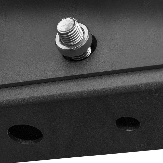 Close-up photo of a Hydra Hardware bolt from Bells of Steel, partially screwed into a black metal surface with two round holes nearby—ideal for installing concrete anchor bolts or rack attachment pins for extra support.