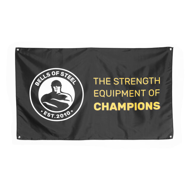 A black Bells of Steel Flags banner with the logo on the left and "THE STRENGTH EQUIPMENT OF CHAMPIONS" in bold white and yellow text—ideal gym decor for any fitness area.