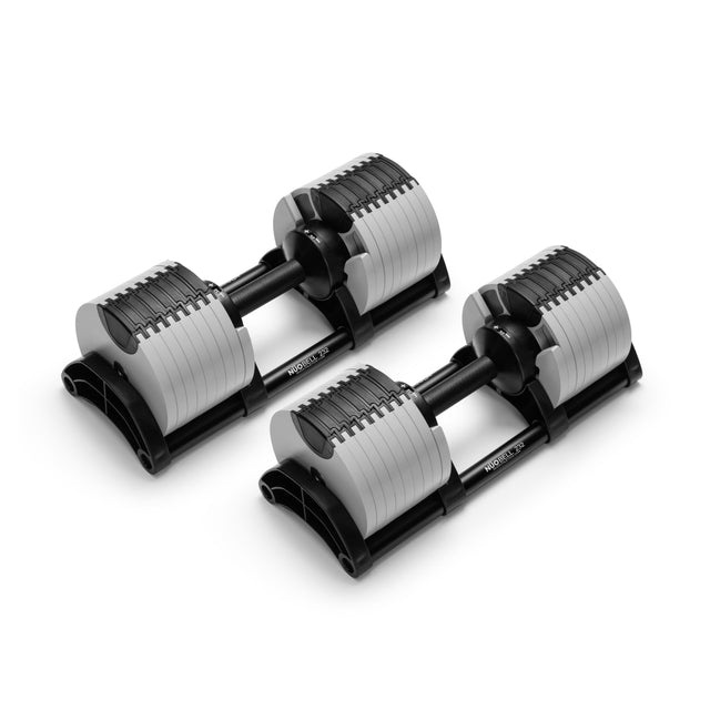 A pair of Nuobell NÜOBELL Adjustable Dumbbells with black handles and machined steel weight plates rests on black plastic bases, displayed against a white background.