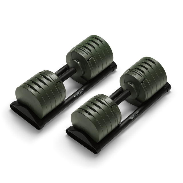A pair of Bells of Steel NÜOBELL-S Adjustable Dumbbells with dark green plates rests on black stands, ideal for any home gym, set against a white background.
