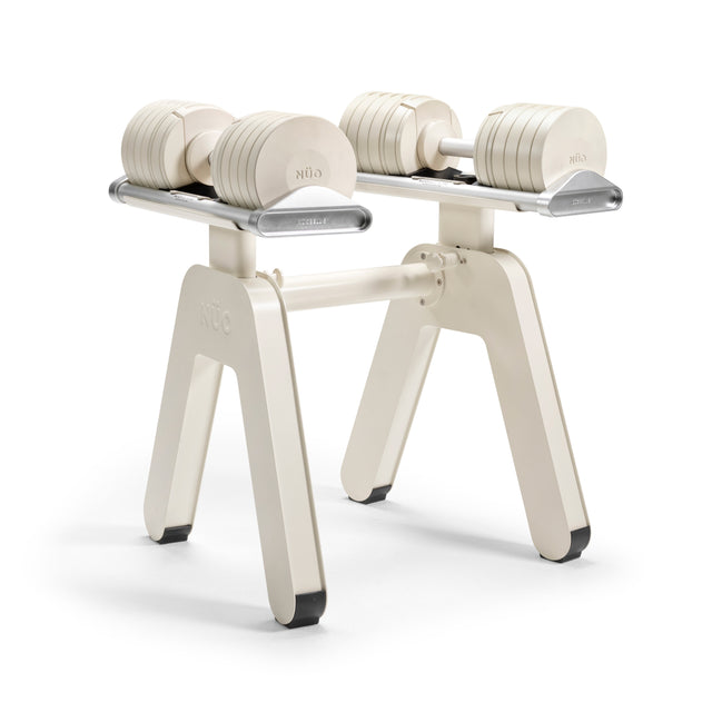 A pair of NÜOBELL-S Adjustable Dumbbells by Bells of Steel rest parallel on the modern, white and silver NÜOBELL-S Floor Stand, equipped with a convenient Floor Stand Converter Kit and supported by four legs.