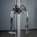 A close-up of Bells of Steel Cable Tower Squat Stands shows adjustable cable machine pulleys with handles and straps on a numbered, vertical metal frame, perfect for home gyms seeking a versatile workout solution.