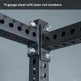 Close-up of a steel gym rack joint with bolts, featuring laser-cut numbered holes on the metal. Text at the top reads, "11 gauge steel with laser cut numbers." The Bells of Steel Manticore Four Post Power Rack - Prebuilt (3" x 3", 1" Holes) is the perfect addition to your home gym, offering exceptional durability and modular versatility for any workout setup.