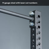 Close-up of the Bells of Steel Manticore Squat Stand - Prebuilt, constructed from durable 3" x 3" 11-gauge black steel uprights with precise laser-cut numbered 1" holes and a horizontal bar secured by bolts—perfect for any home gym. Text at the top reads, "11 gauge steel with laser cut numbers.