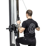 Wearing a black t-shirt and pants, a person kneels on one knee while using Bells of Steel Aluminum Handles Pair attached to a cable machine for a lat pulldown, pulling the handles down with both arms.