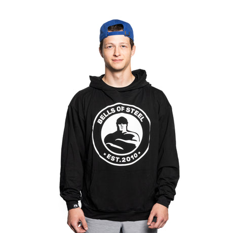 A young man wearing a blue backwards cap and a black Bells of Steel Bamboo Hoodie stands facing forward against a plain white background.