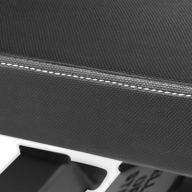 Close-up of a black premium vinyl seat cushion with white stitching on the Buzz-Saw Heavy-Duty Adjustable Bench by Bells of Steel, showing part of the sturdy frame below.