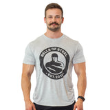 A mustached man smiles against a white background, wearing a light gray Bells of Steel Bamboo T-Shirt featuring the "Bells of Steel Est. 2010" logo.