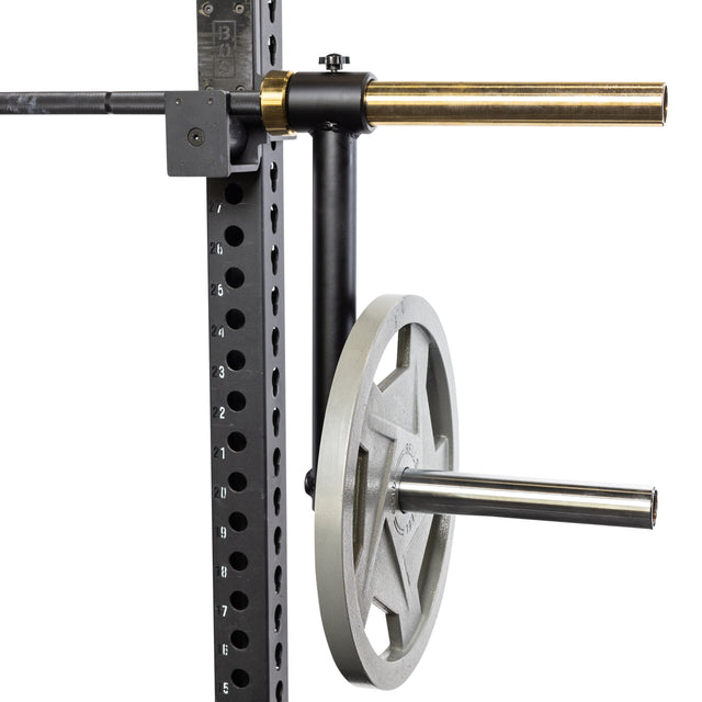 A close-up of the Bells of Steel Camber Bar Attachment - Pair mounted to a gym power rack, storing a single gray weight plate on its horizontal peg. The numbered industrial rack is ideal for organizing Olympic barbell plates.