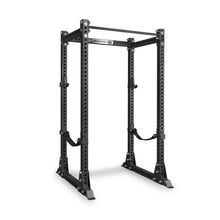 The Bells of Steel Manticore Flat Foot Power Rack - Prebuilt (3" x 3", 1" Holes) is a black steel, free-standing rack featuring multiple adjustment holes, a pull-up bar across the top, and safety straps. Designed for weightlifting and strength training, this power rack is photographed on a white background—an ideal addition to any home gym.