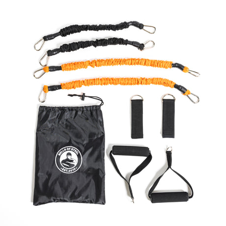 The Bells of Steel Soft Glute Bench set includes two orange and two black resistance bands with carabiner clips, a logo drawstring bag, two handles, and two ankle straps—ideal for home workouts like hip thrusts.
