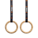 Bells of Steel's wooden Gymnastics Rings, with "BELLS OF STEEL" engraved, hang from black and orange straps featuring the logo. The setup is perfect for a core workout and stands out against the white background.