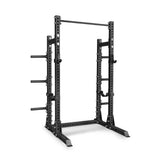 The Bells of Steel Manticore Half Rack Builder is a black metal power rack featuring robust 3" x 3" uprights with 1" holes, adjustable supports, a pull-up bar, and weight plate storage pegs—perfectly designed for strength training and weightlifting in your home gym.