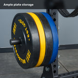 A close-up of the Bells of Steel Manticore Half Rack - Prebuilt (3" x 3", 1" Holes) showcases its sturdy uprights, holding several large black, yellow, and blue weight plates in a gym setting. The image features the text “Ample plate storage” at the top—making it a perfect addition to any home gym.