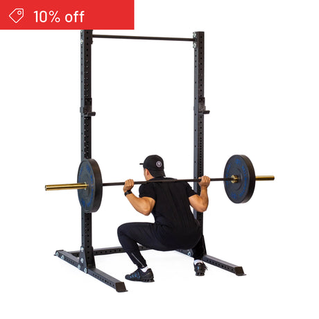 A person in black workout gear uses the Bells of Steel Hydra Squat Stand Builder (3" x 3", ⅝" Holes) to squat with a barbell in their home gym. A "10% off" discount label is shown in the top left corner.