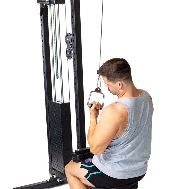 A man in a gray tank top and black shorts uses a Bells of Steel Single D Handle Cable Attachment, pulling it toward his chest at a cable machine while performing a seated cable row.