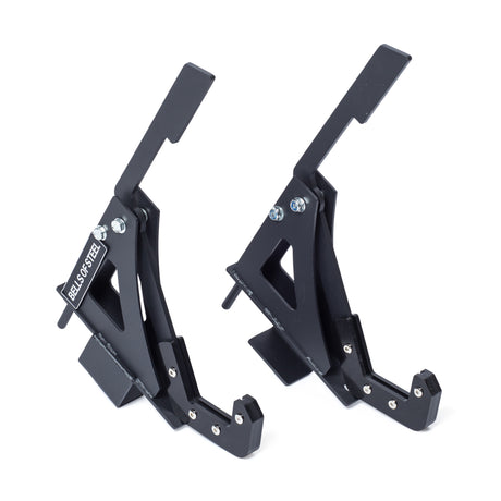 Two black metal Monolift Rack Attachments by Bells of Steel, with angular space-saving designs and bolts, stand upright on a white background. One displays the "BELLS OF STEEL" label.