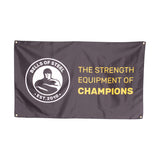 A black Bells of Steel flag featuring its logo on the left and "THE STRENGTH EQUIPMENT OF CHAMPIONS" in bold yellow and white lettering—ideal for gym decor or upgrading your home gym.