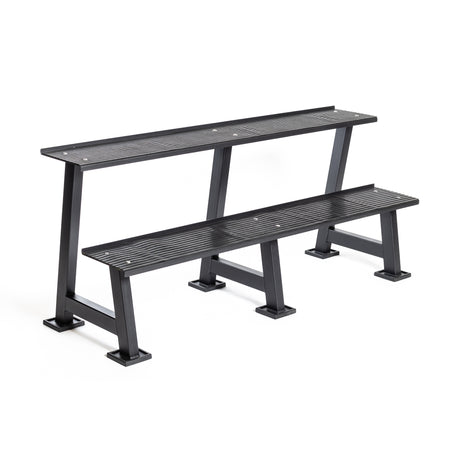 The Bells of Steel Kettlebell Rack is a two-tiered black metal bench with slatted seats and sturdy legs, ideal for public or home gym use, and doubles as a practical competition kettlebell storage solution.