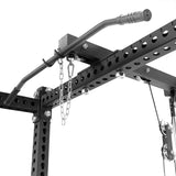 Close-up of a black metal pull-up bar on a power rack with numbered holes, a chain, and the Bells of Steel Lat Pulldown & Low Row Rack Attachment—Hydra & Manticore—mounted nearby for cable exercises.