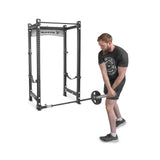 A man in athletic wear performs a strength workout, lifting a barbell from the UHMW-lined Landmine Rack Attachment by Bells of Steel, using both hands with unwavering focus.