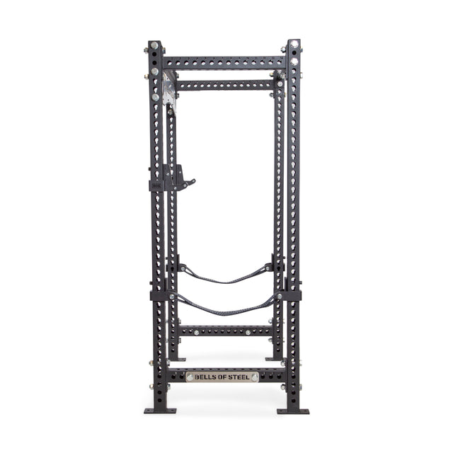 A Manticore Four Post Power Rack - Prebuilt (3" x 3", 1" Holes) from Bells of Steel, featuring modular components such as adjustable crossbars and safety straps, designed for weightlifting and strength training in home gyms. The "Bells of Steel" branding is prominently displayed at the base, set against a white background.