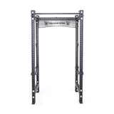 The Manticore Four Post Power Rack - Prebuilt by Bells of Steel, crafted from black steel, is perfect for home gyms. It boasts a modular design with a pull-up bar and features 1" holes for adjustable attachments. The top includes a branded plate displaying the "Bells of Steel" logo.