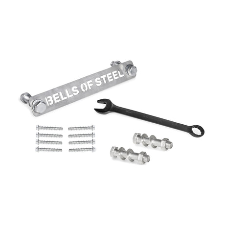 The Bells of Steel Manticore Hardware kit includes a labeled metal bar, black wrench, bolts, nuts, screws, and concrete anchor bolts—everything you need to assemble your Manticore Power Rack on a white surface.