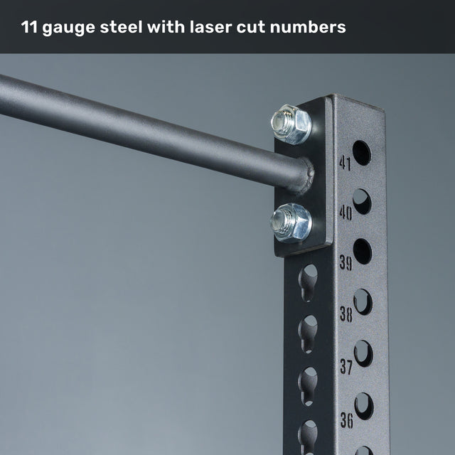 Close-up of the Bells of Steel Manticore Squat Stand - Prebuilt, featuring robust black 3" x 3" 11-gauge steel uprights with precise laser-cut numbered 1" holes, heavy-duty bolts, and a sturdy horizontal bar—perfect for any home gym. Text above reads: "11 gauge steel with laser cut numbers.