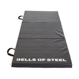 The Bells of Steel Trifold Mat is a black, non-slip exercise mat with side handles and "BELLS OF STEEL" in white text—perfect for gymnastics or workouts.