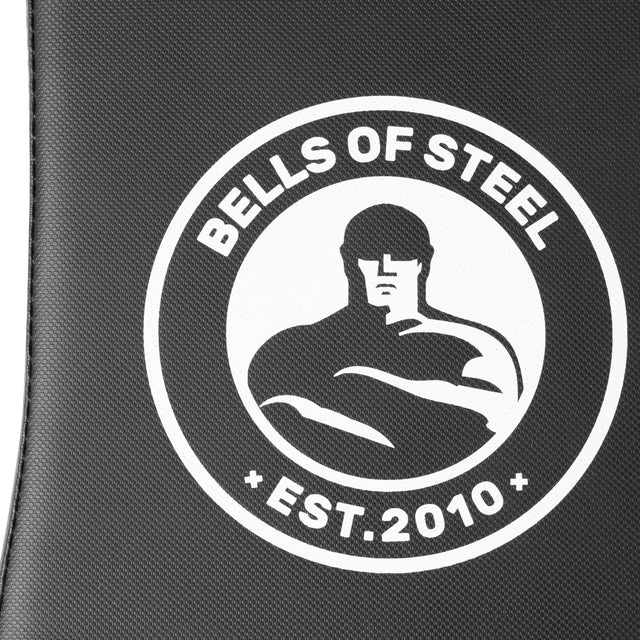 Close-up of the Bells of Steel logo showing a muscular figure inside a circle, with "BELLS OF STEEL" on top and "EST. 2010" below, set against a textured dark background—ideal for your Bells of Steel Adjustable Utility Bench.