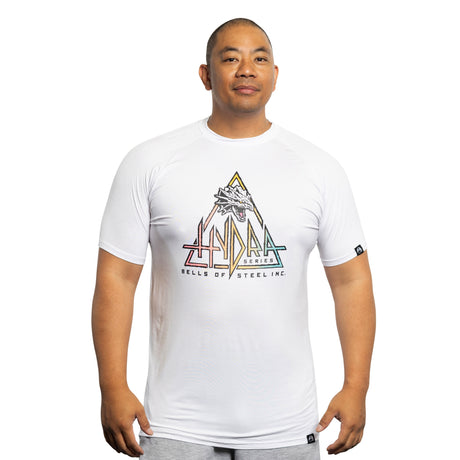 A man faces forward against a plain white background, wearing a white Bamboo T-Shirt from Bells of Steel featuring a colorful geometric Hydra design and the text "HYDRA SERIES BELLS OF STEEL INC.