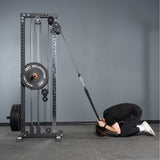 Wearing black workout gear, a person kneels in child's pose, using the Bells of Steel Extra Long Tricep Rope Extension (137cm) attached to a weight machine to perform a cable crunch exercise.